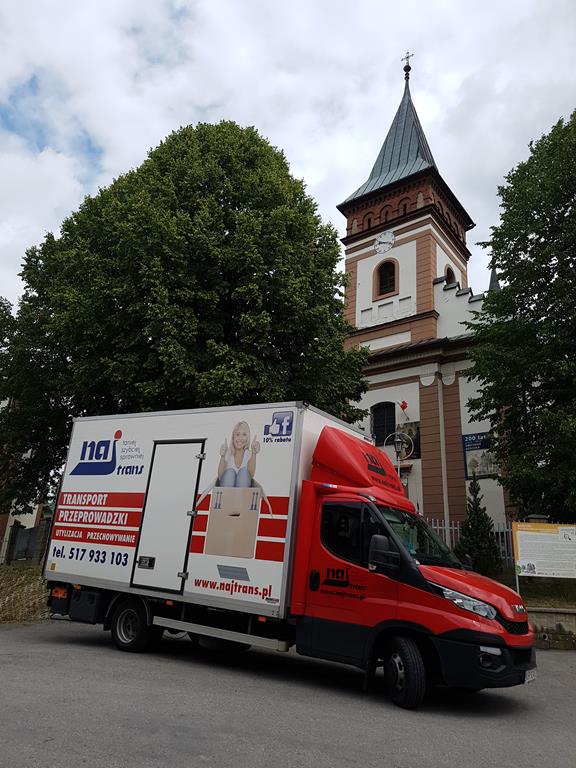Ciężarówka Najtrans przed zabytkowym kościołem z wieżą