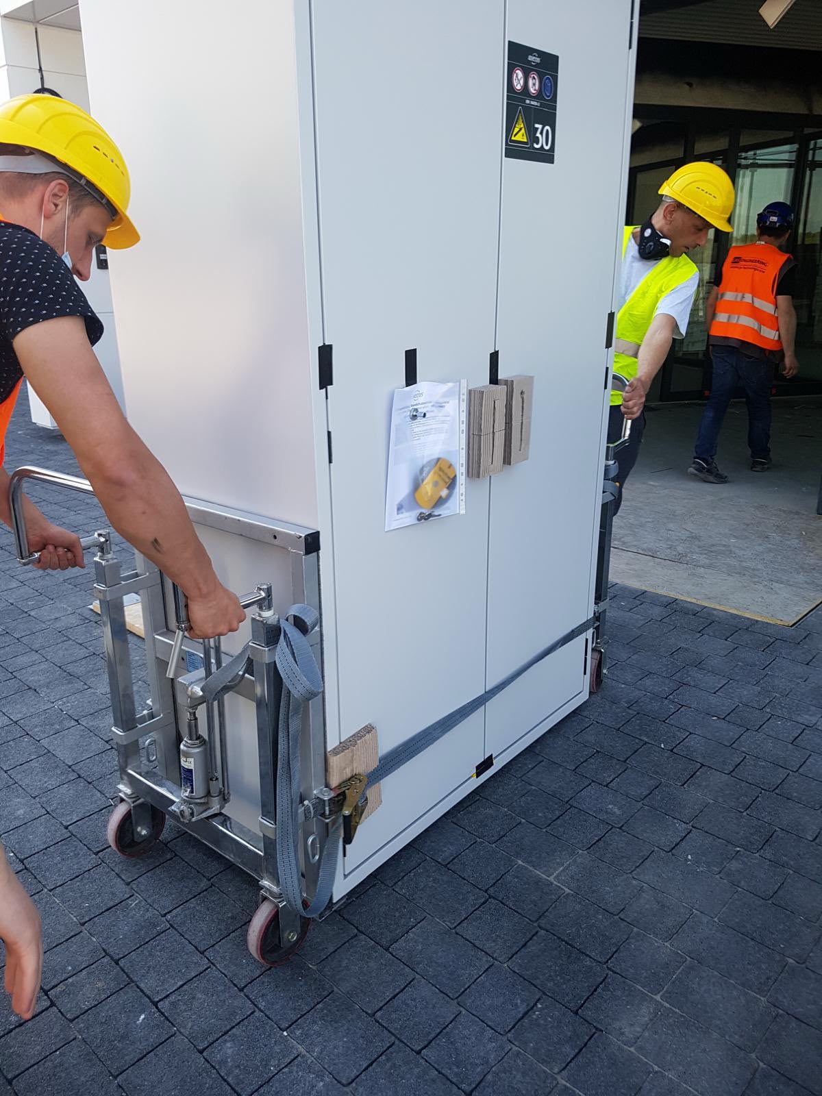 Transport szafy serwerowej na wózku hydraulicznym przez ekipę Najtrans w kaskach
